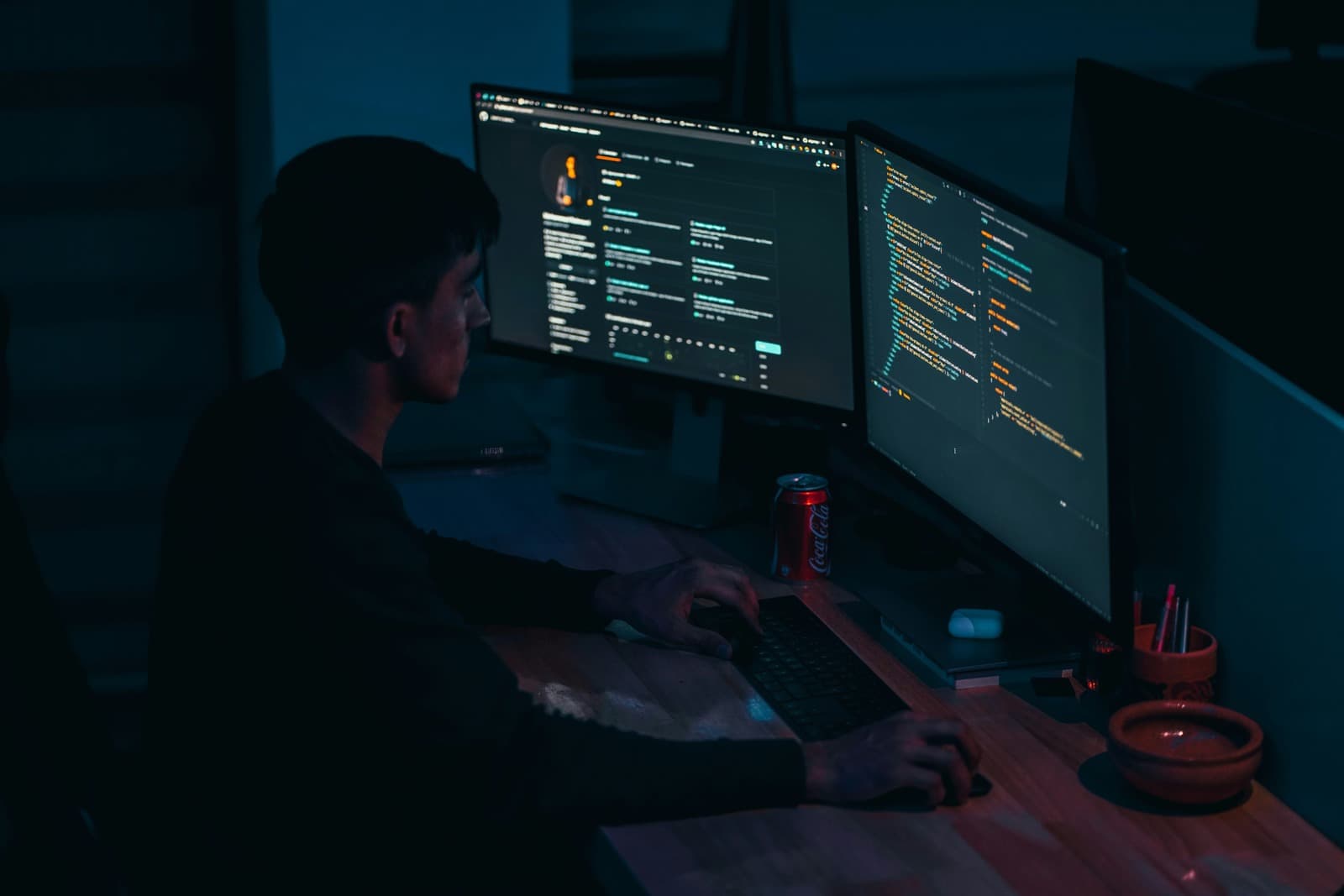 Developer working at desk with monitor and laptop